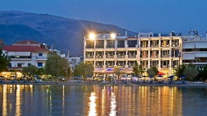 Ein mehrstöckiges Hotel mit Balkonen in Wassennähe, Spiegelungen im Wasser sichtbar.
