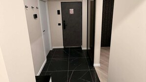 A modern hallway with black marble flooring, a dark door with a no entry sign, and a light switch on the wall. - SteRo Luxury Residence | Modern Apt | Self Check-In | Free Minibar (Galați)