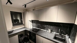 A modern kitchen with a gas stove, a kettle, and a sink. - SteRo Luxury Residence | Modern Apt | Self Check-In | Free Minibar (Galați)