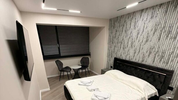 A modern bedroom with a large bed, a desk, and a chair. - SteRo Luxury Residence | Modern Apt | Self Check-In | Free Minibar (Galați)