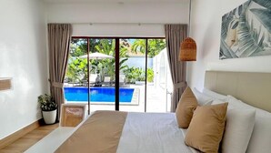 Un dormitorio con una cama grande, vistas a una piscina y una lámpara de mimbre.