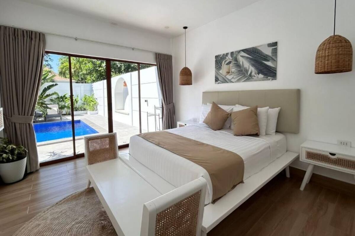 Une chambre moderne avec un grand lit, un banc, une vue sur une piscine et un ventilateur de plafond.