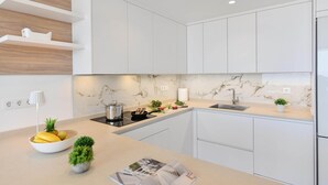 A modern kitchen with white cabinets, a marble backsplash, and a built-in oven. - Cozy Maspalomas Bungalow With Pool (San Bartolomé de Tirajana)