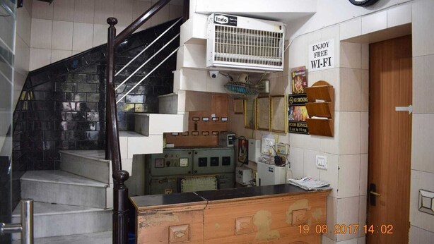 A staircase with a wooden handrail, a wall-mounted air conditioning unit, and a sign indicating room service hours.