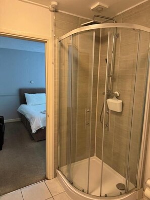A glass-enclosed shower with a handheld showerhead and a handheld soap dispenser. - Cottage Court Hotel (Tenby)