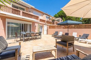 A patio with outdoor furniture, a table, and a chair. - Courtille Plage – Natural Retreat by the Sea in Fréjus (Fréjus)
