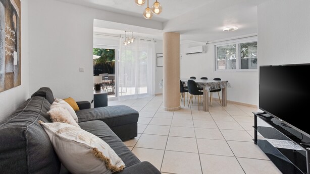 A modern living room with a sofa, TV, and dining area. - Courtille Plage – Natural Retreat by the Sea in Fréjus (Fréjus)