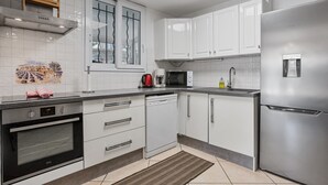 A modern kitchen with white cabinetry, a built-in oven, a microwave, and a stainless steel refrigerator. - Courtille Plage – Natural Retreat by the Sea in Fréjus (Fréjus)