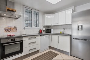 A modern kitchen with white cabinetry, a built-in oven, a microwave, and a stainless steel refrigerator. - Courtille Plage – Natural Retreat by the Sea in Fréjus (Fréjus)