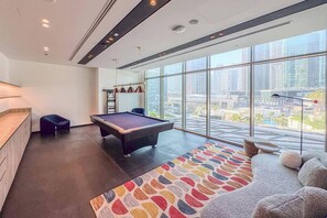 Ein modernes Zimmer mit Billardtisch, großen Fenstern und Blick auf die Stadt.