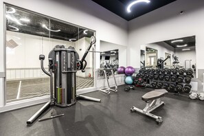 Ein Fitnessstudio mit Trainingsgeräten, Gewichten und einem Spiegel.
