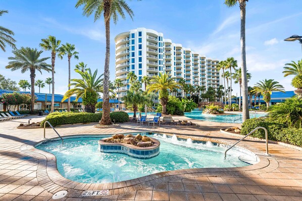 A hotel pool area with multiple pools, palm trees, and lounge chairs. - Palms of Destin Condo w/ Lagoon Pool (Destin)