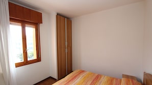 Een slaapkamer met een bed, een kledingkast en een raam.