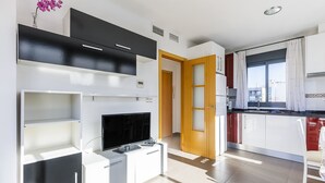 Een moderne keuken met witte kasten, een zwart aanrecht en een ingebouwde televisie.