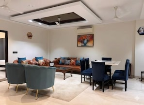 Een moderne woonkamer met een bank, stoelen, een salontafel en een eethoek met een tafel en stoelen.