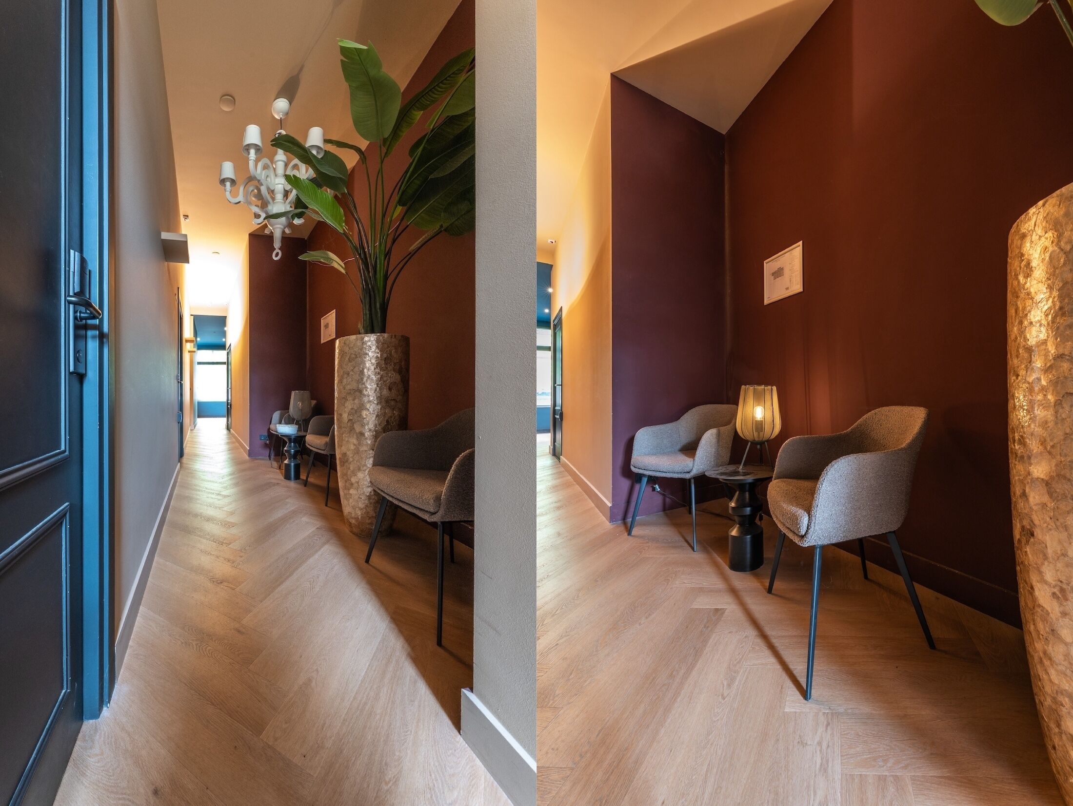 Een hotelgangen met houten vloer, een grote potplant en twee zithoekjes met tafels en stoelen.