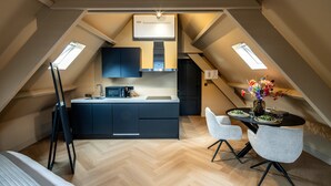 Un appartement moderne de style « loft » comprenant une cuisine, un coin repas et un lit en mezzanine.