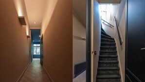 Un couloir doté d’un plancher en bois, une porte au fond et un escalier muni d’une main courante.