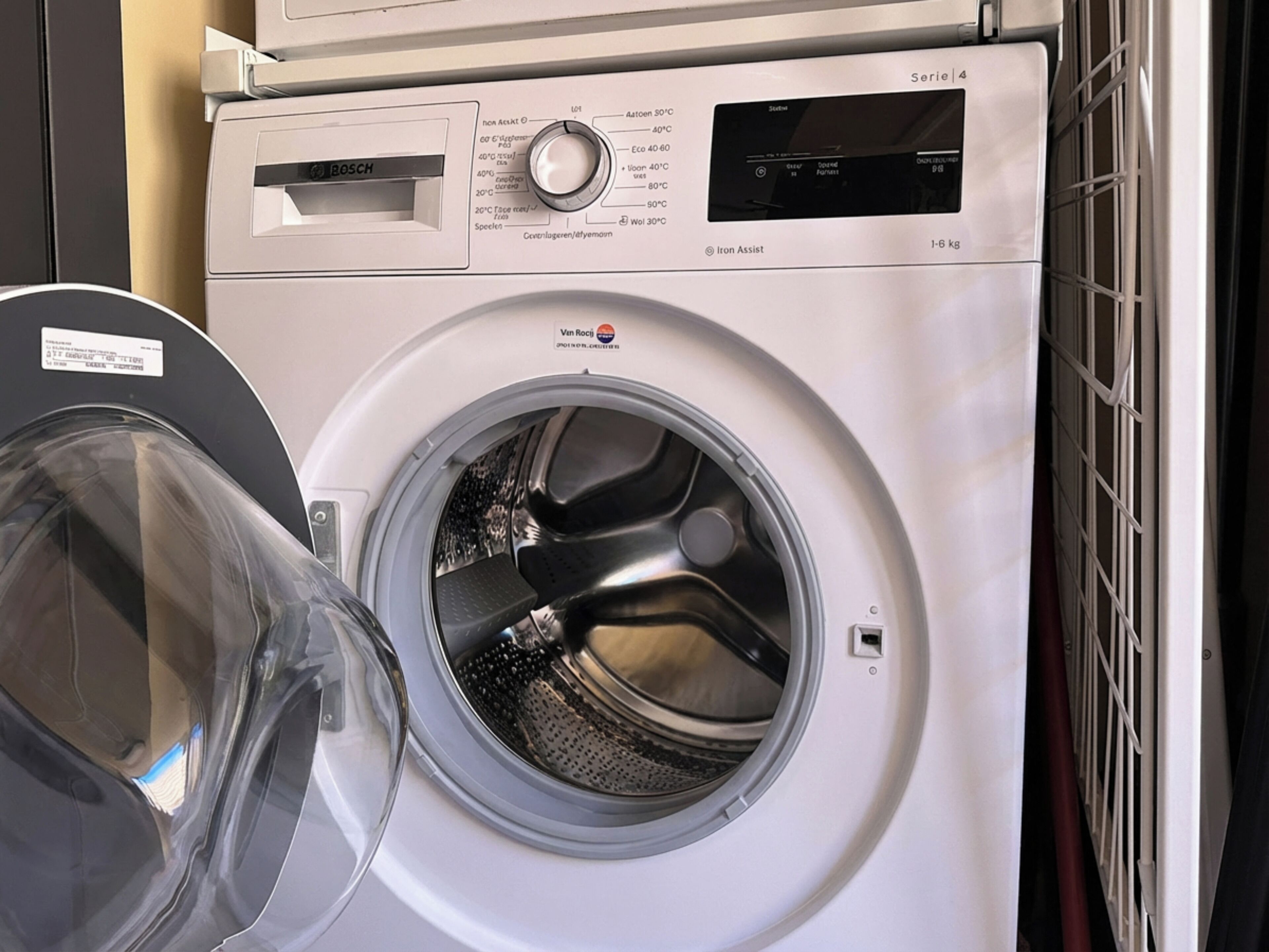 Une machine à laver à chargement frontal, dotée d’un panneau de commande et d’une porte transparente.