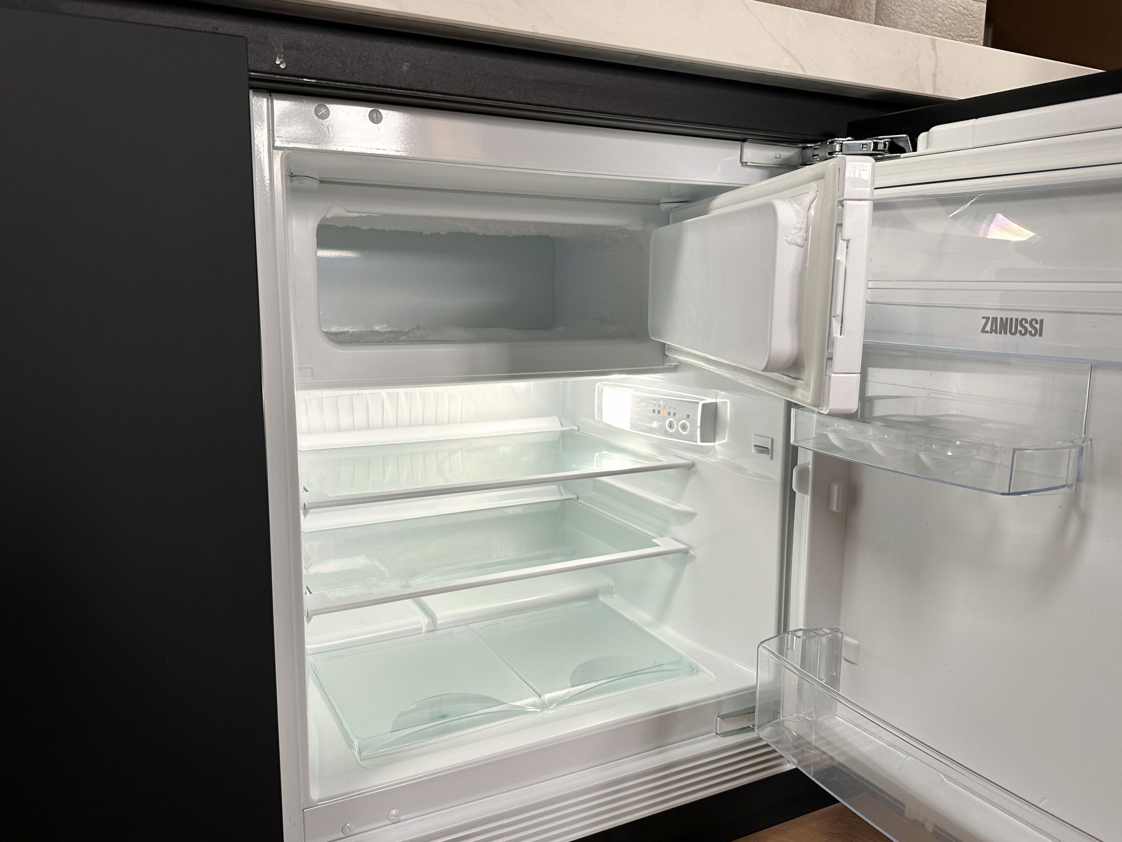 Un refrigerador abierto con repisas transparentes y un panel de control.