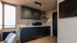 A modern kitchen with black cabinets, a stainless steel range hood, a microwave, and a coffee maker. - Just a few minutes walking from Breda’s city centre, with shops, cafés, restaurants, and nightlife nearby. Close to Breda Central Station. Explore the Grote Markt, enjoy Burgundian dining, and relax on lively terraces, all within walking distance. (Breda)
