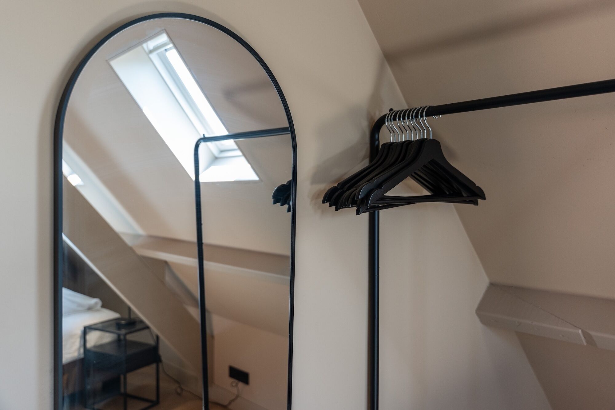 Een moderne kamer met dakraam, kapstok en een spiegeldeur voor de inloopkast.