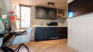 A modern kitchen with dark cabinets, a microwave, and a coffee maker on the counter. - Just a few minutes walking from Breda’s city centre, with shops, cafés, restaurants, and nightlife nearby. Close to Breda Central Station. Explore the Grote Markt, enjoy Burgundian dining, and relax on lively terraces, all within walking distance. (Breda)