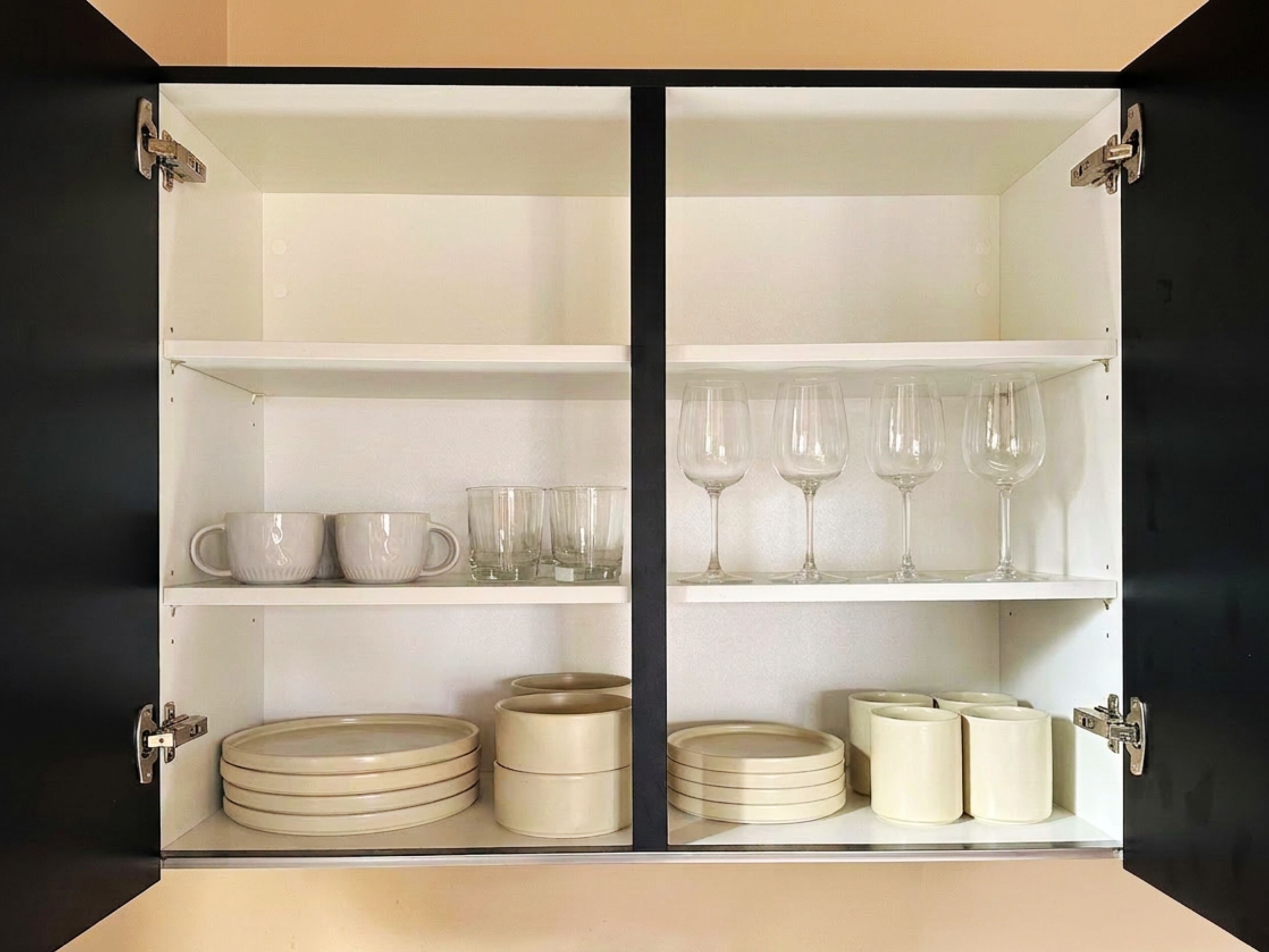 Un meuble avec deux étagères, chacune contenant des assiettes, des tasses et des verres.