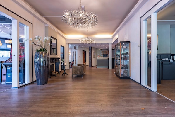 Un hall d’entrée spacieux, agrémenté d’un grand lustre, d’un comptoir d’accueil et d’une vitrine.