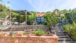 A stone staircase leading up to a wooden deck with outdoor furniture and potted plants. - Oleandro by Interhome (Castiglione della Pescaia)