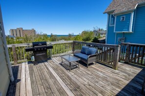 A wooden deck with a grill, a table, and a sofa. - Adorable Hilltop Cottage by the Beach (Michigan City)