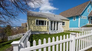 A residential house with a white picket fence, a small front porch, and a well-maintained lawn. - Adorable Hilltop Cottage by the Beach (Michigan City)