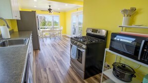 A kitchen with a stove, oven, microwave, and a slow cooker on a shelf. - Adorable Hilltop Cottage by the Beach (Michigan City)
