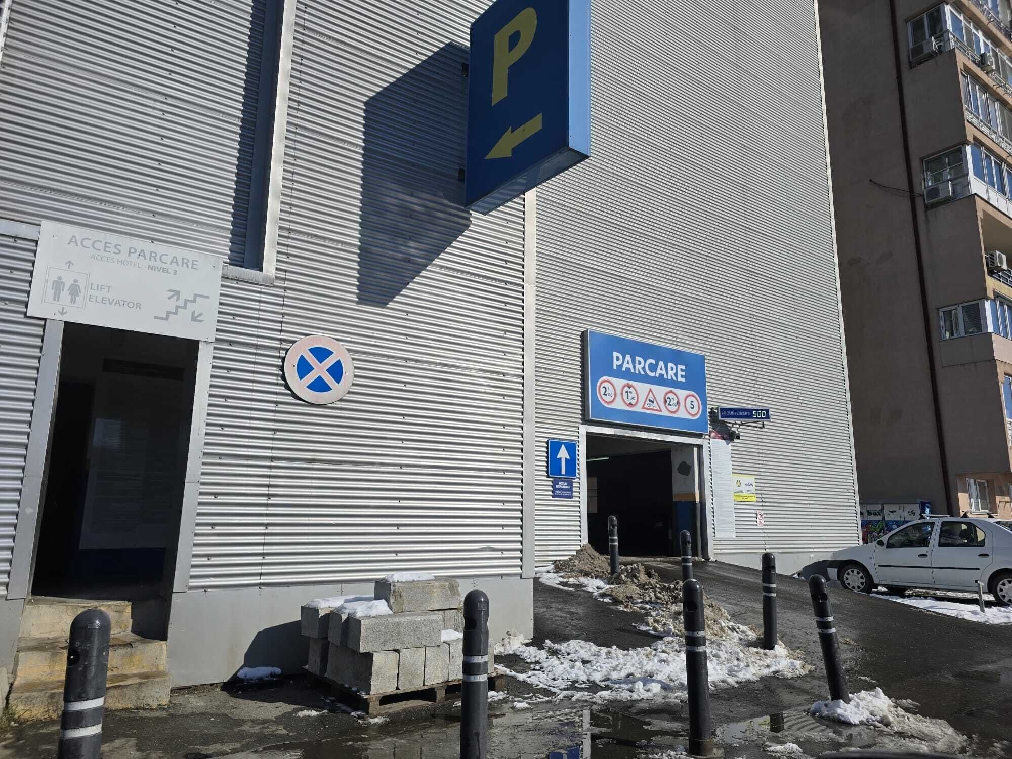 A building with a sign indicating a parking area, a lift, and access to a hotel.