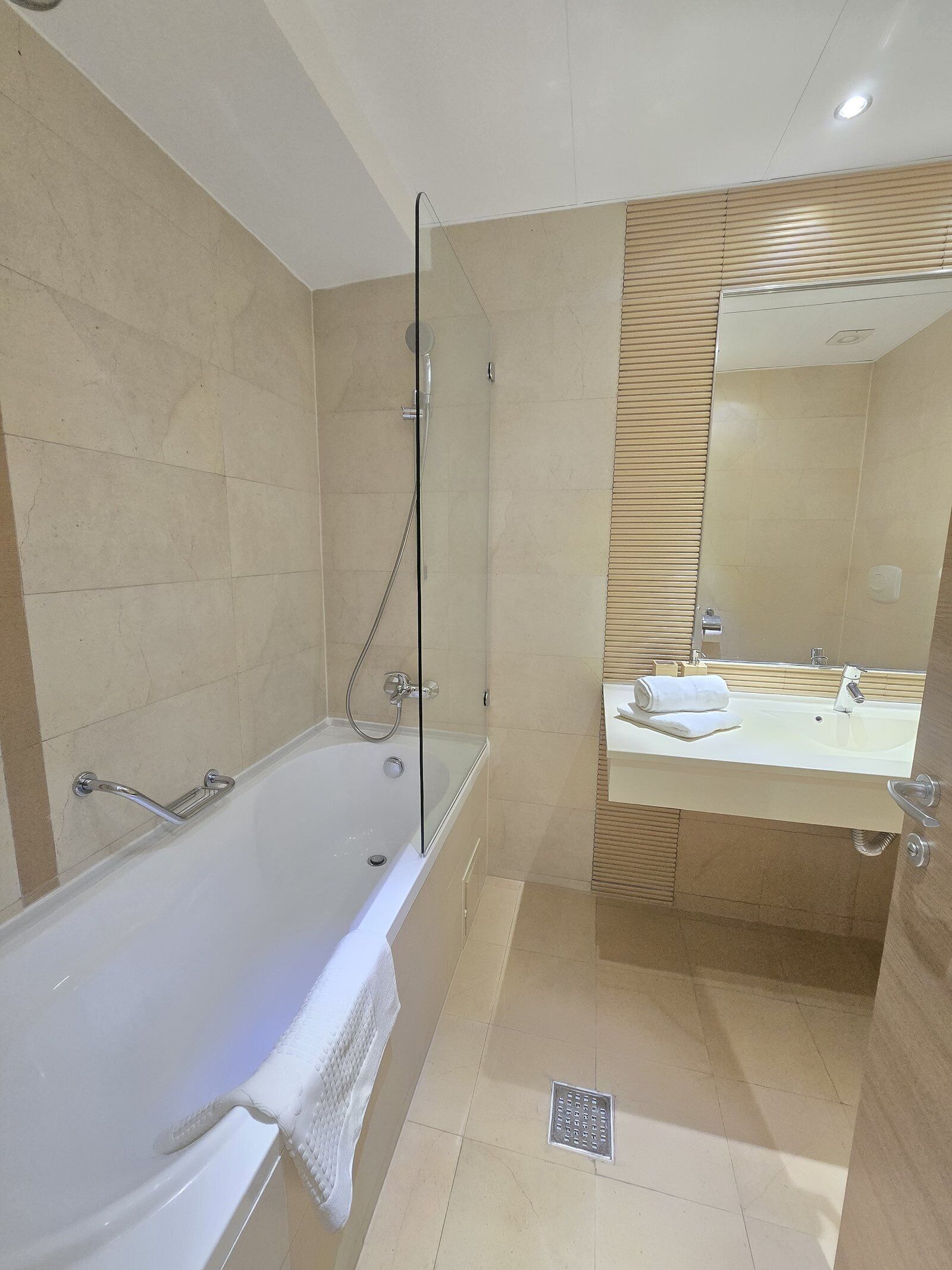 A modern bathroom with a bathtub, shower, and a vanity with a mirror.