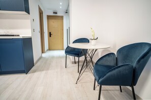 A modern room with a dining table, two blue chairs, a potted orchid, and a wooden door. - LaRin Residence Apartments (Bucharest)