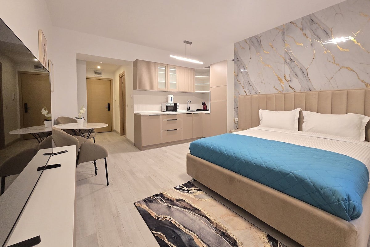 Ett modernt hotellrum med en stor säng, ett skrivbord och ett litet pentry.