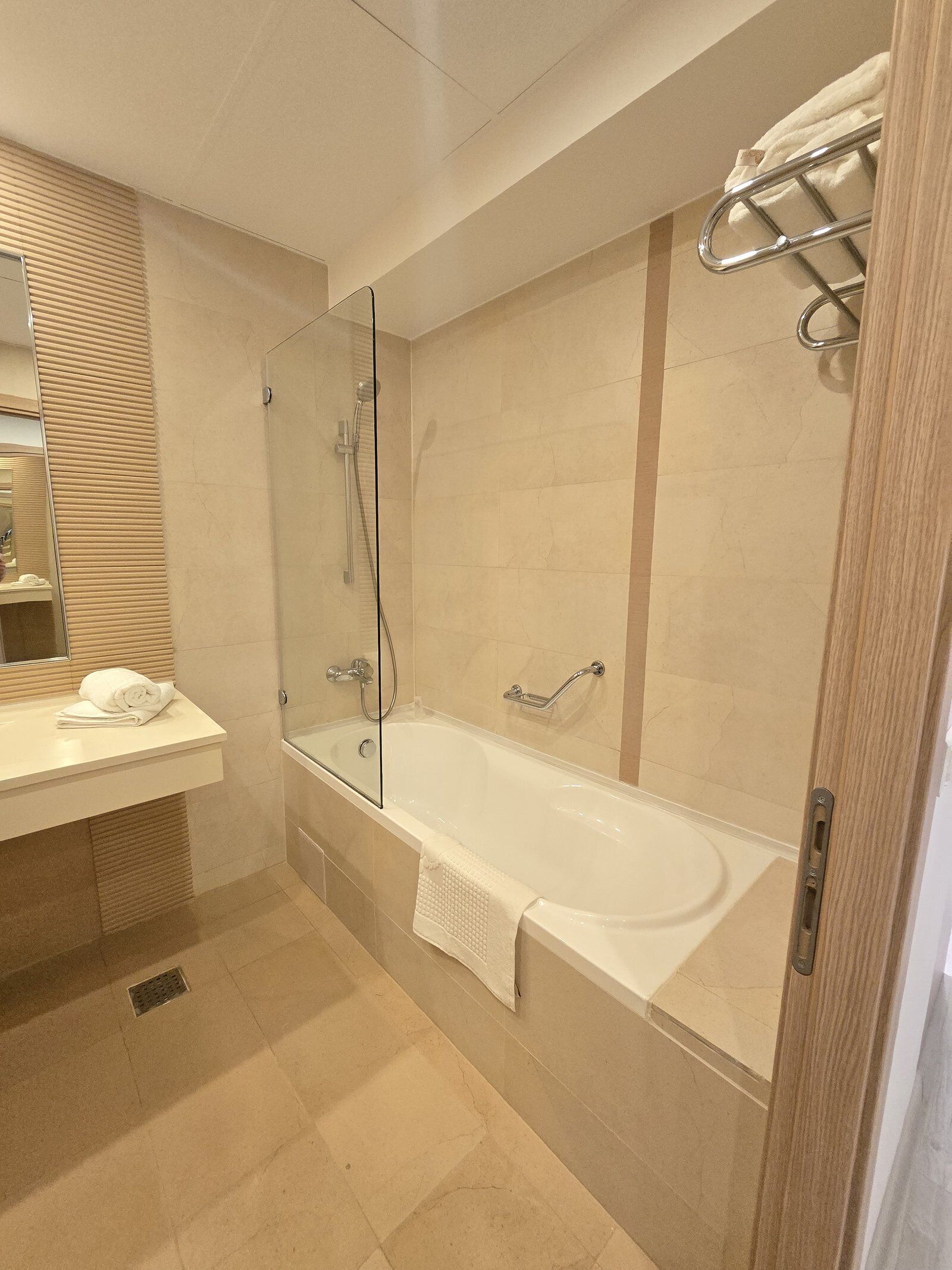 A modern bathroom with a glass-enclosed shower, a white bathtub, and a vanity with a towel.