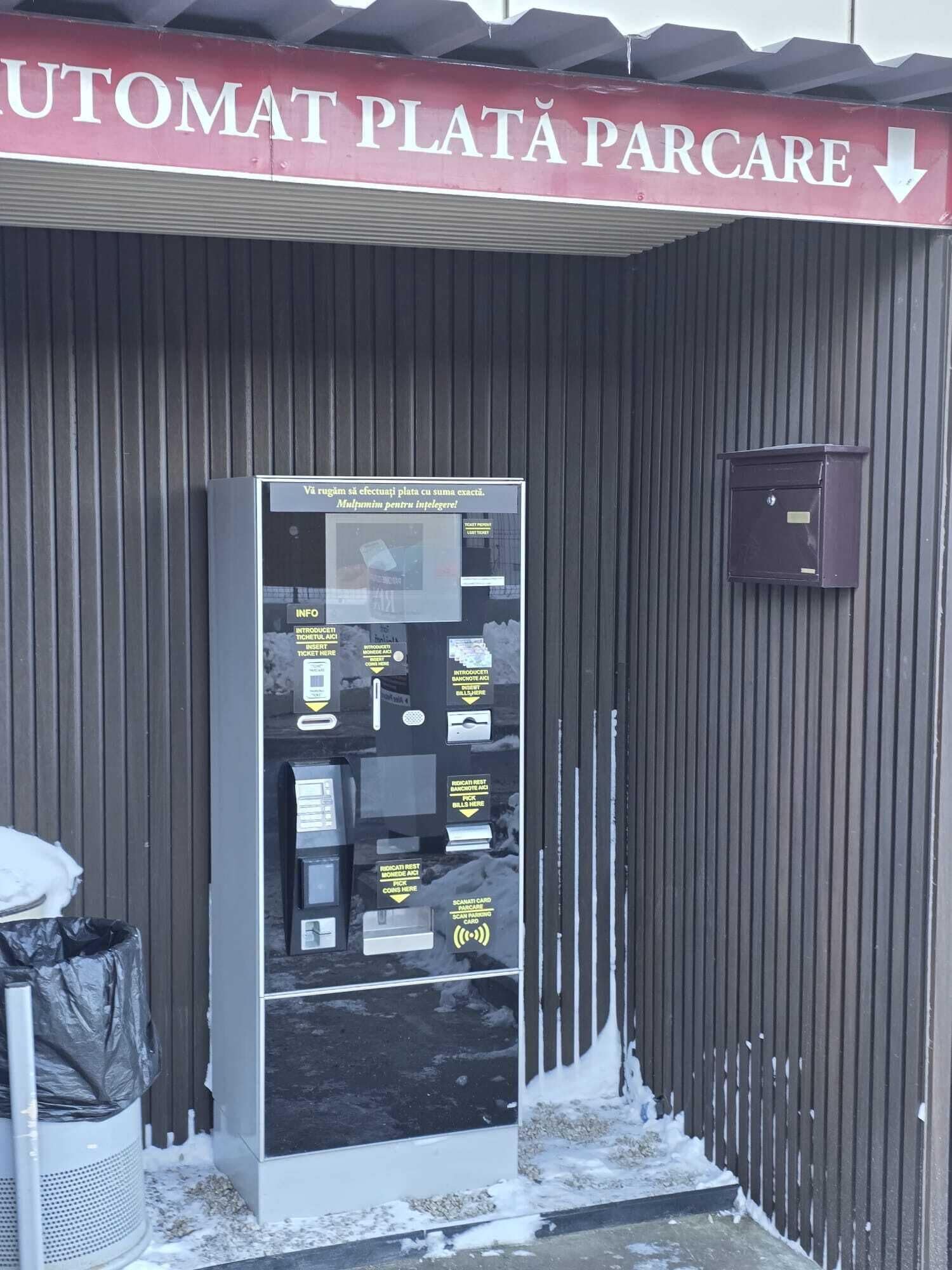 Un cajero automático en la entrada de un estacionamiento, con un letrero encima.