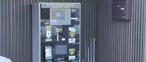 Un cajero automático en la entrada de un estacionamiento, con un letrero encima.