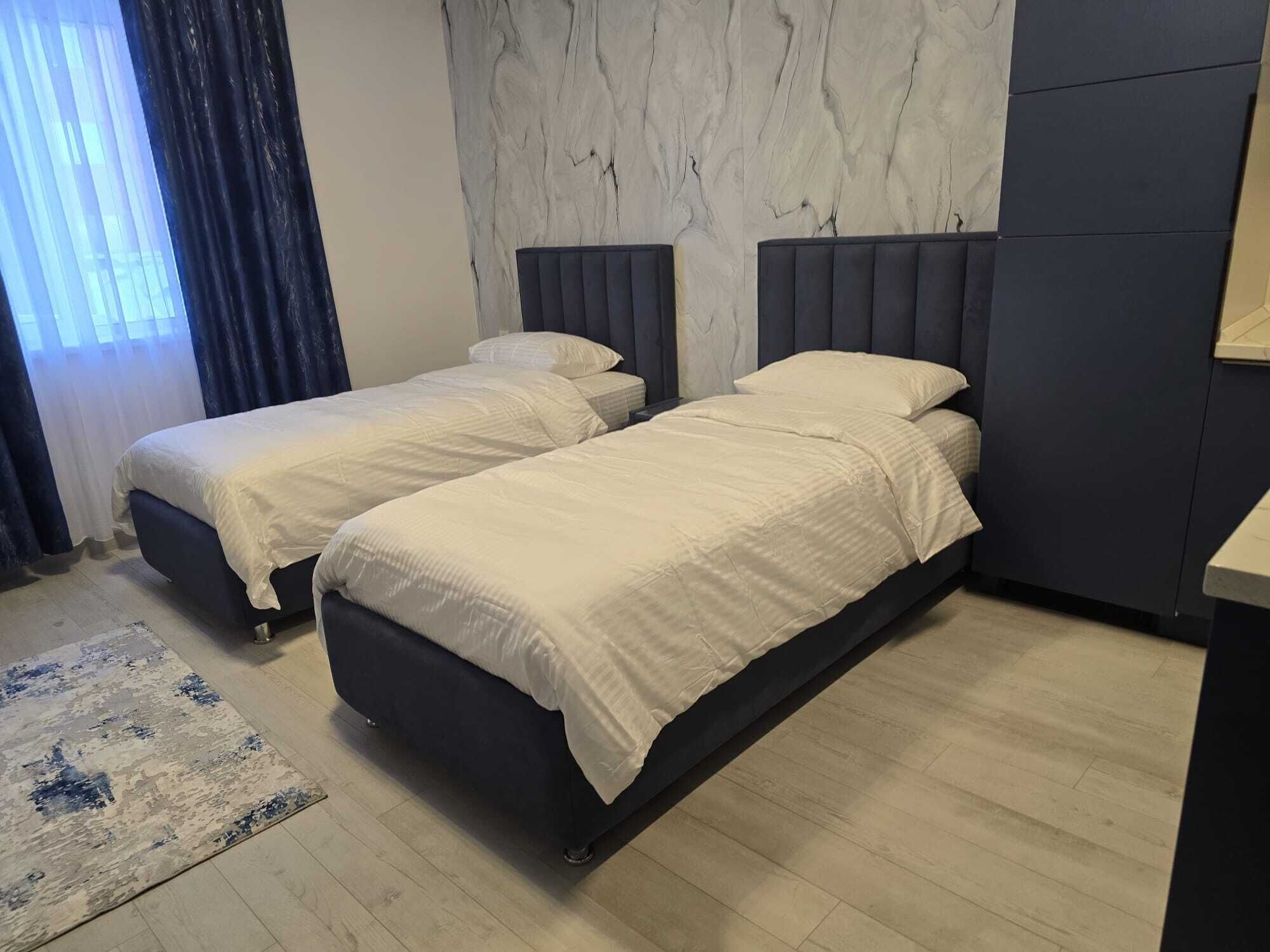 Una camera d'albergo con due letti, una parete in marmo e un pavimento in legno.
