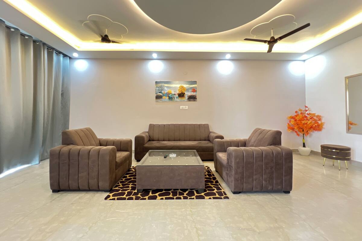 A modern living room with a sofa set, a coffee table, a giraffe-patterned rug, ceiling fans, recessed lighting, and a wall-mounted painting.