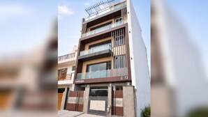 A modern multi-story building with a flat roof, large windows, and a visible address sign. - Book N Go HomeStay - Greater Noida (Greater Noida)