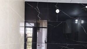 A bathroom with a black marble wall, a white sink, and two wooden stools. - Book N Go HomeStay - Greater Noida (Greater Noida)