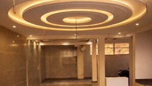 A spacious lobby with a circular ceiling design, a reception desk, and a clean, polished floor. - Book N Go HomeStay - Greater Noida (Greater Noida)