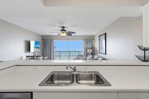 A modern kitchen with a dual sink, a ceiling fan, and a view of the balcony. - Gulf front home with shared pool, private balcony and beach access (Fort Walton Beach)