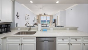 Uma cozinha moderna com uma ilha grande, eletrodomésticos de aço inoxidável e vista para o oceano.