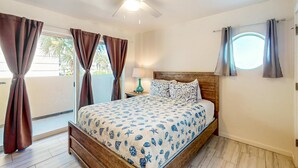 Ein Schlafzimmer mit Bett, Vorhängen, Deckenventilator, Nachttisch und Fenster.