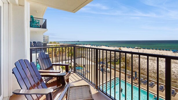 Un balcon avec deux fauteuils Adirondack, une petite piscine et une vue sur la plage et l’océan.