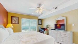 Une chambre d’hôtel avec un lit, une télévision, une commode et une fenêtre avec des stores.